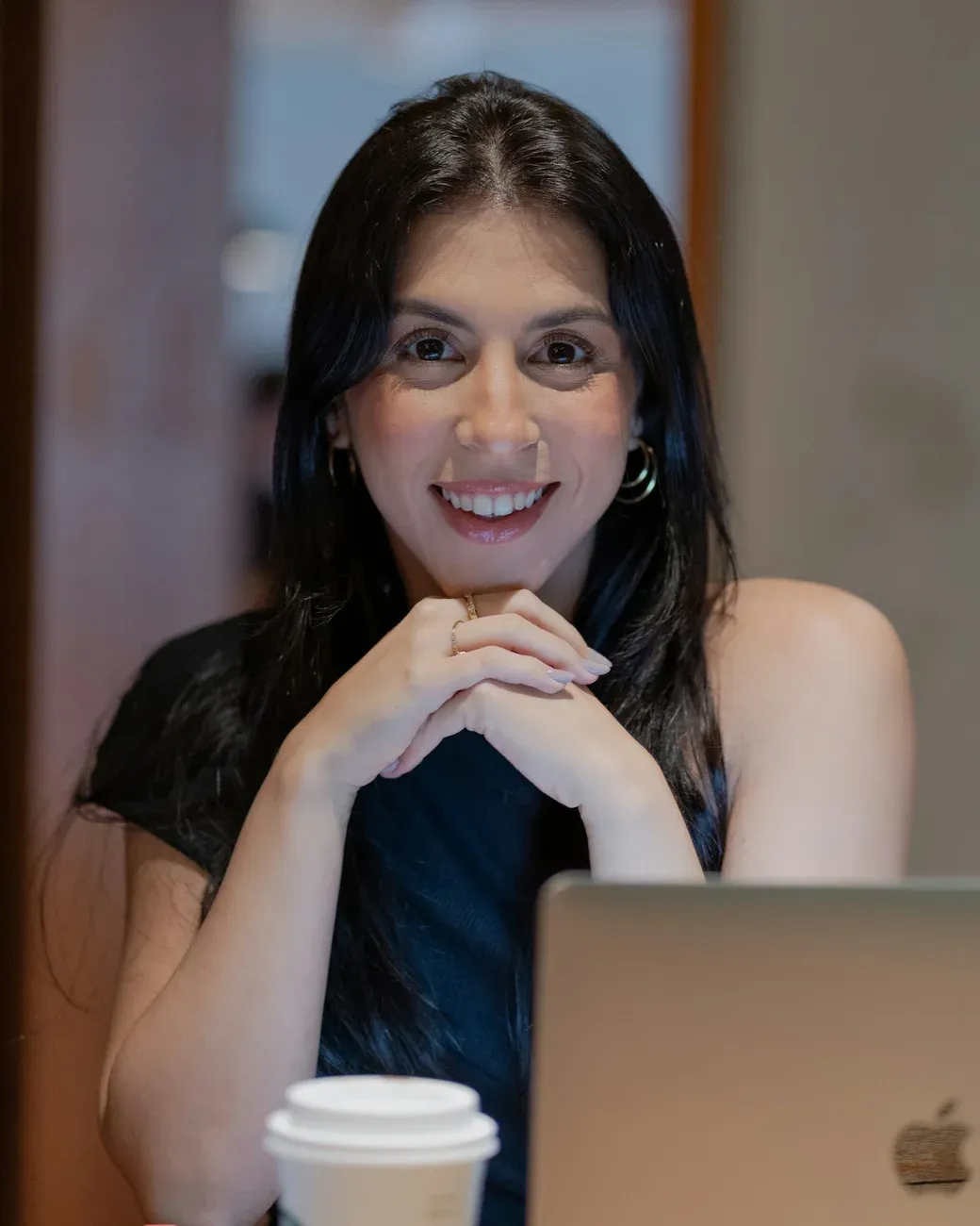 Mujer sonriendo frente a su laptop en una oficina