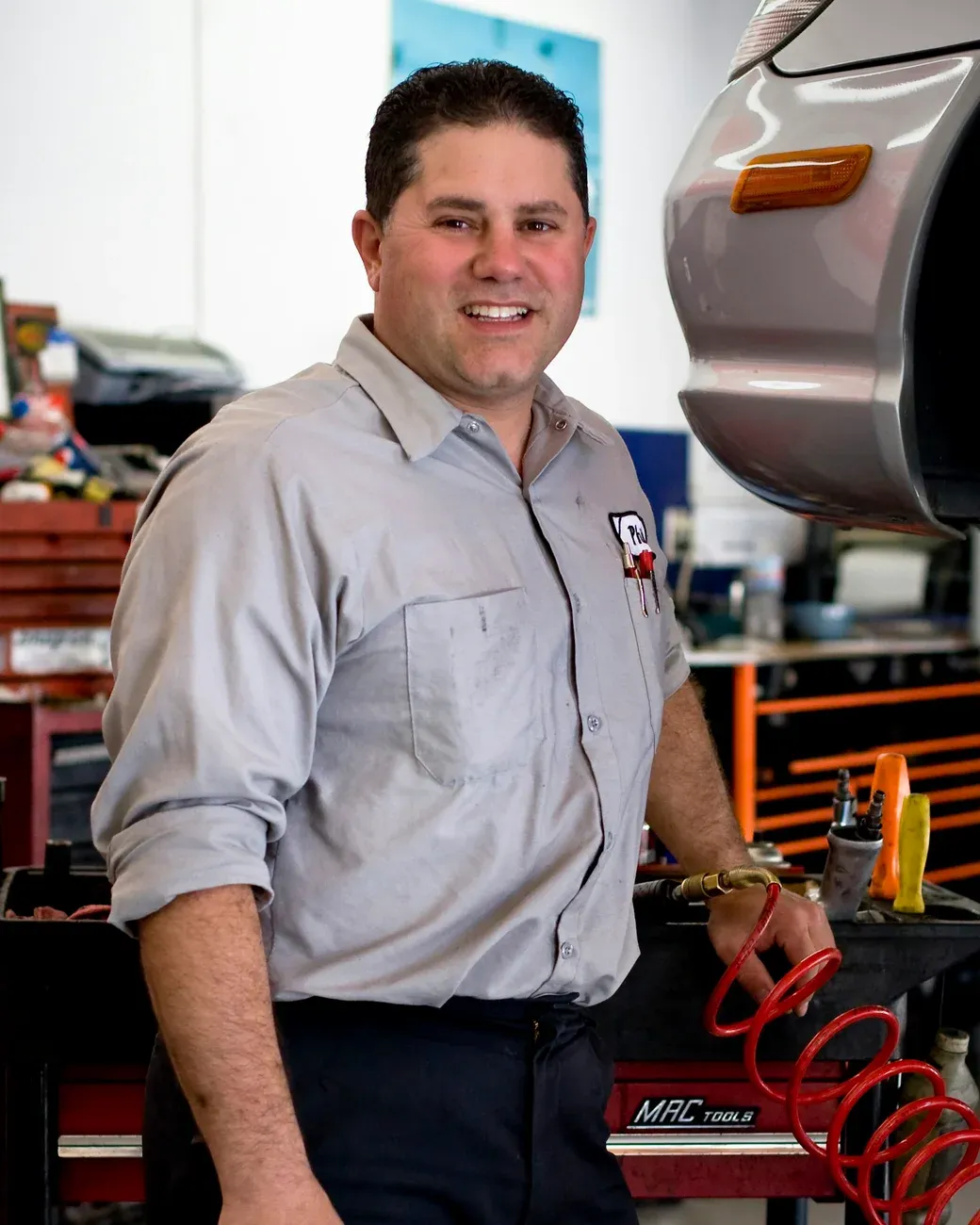 Dueño de un taller mecánico sonriendo junto a su banco de trabajo